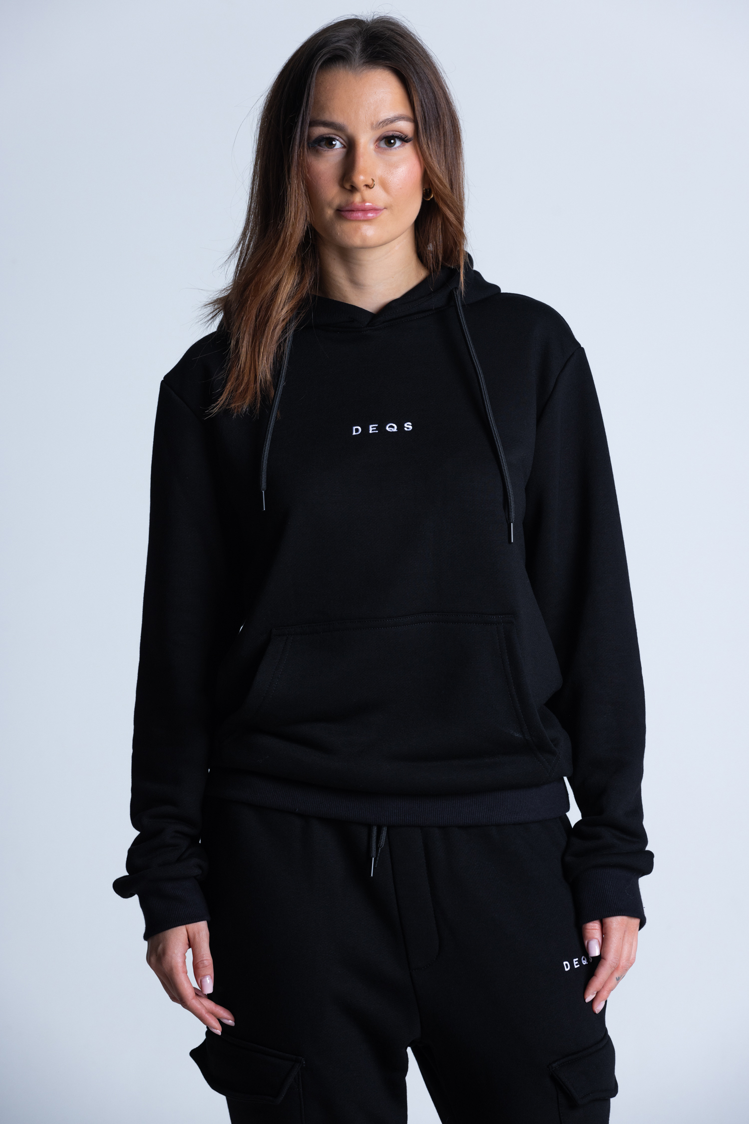Kobieta w czarnej bluzie z kapturem – logo DEQS i komfortowy krój