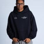 Model przodem w bluzie DEQS – kaptur, logotyp, styl sportowy