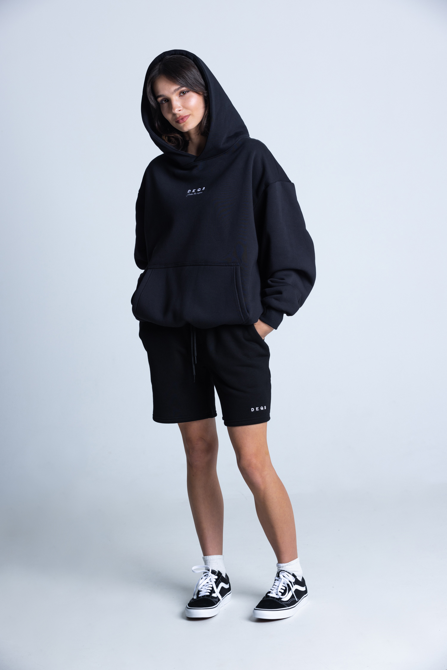Modelka w czarnej bluzie i spodenkach DEQS – zestaw streetwear