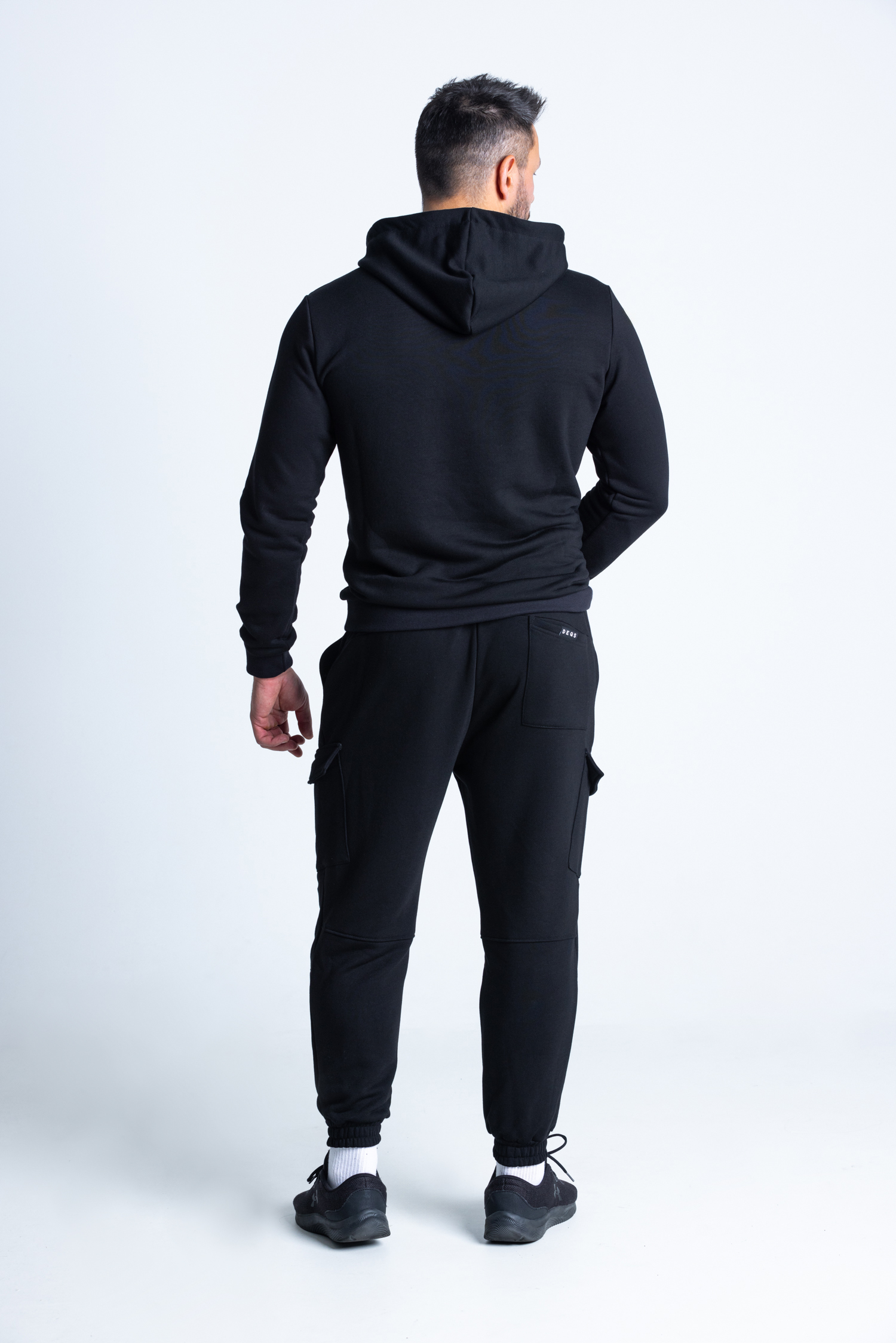 Mężczyzna w komplecie DEQS – bluza z kapturem i dopasowane spodnie