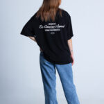 Kobieta bokiem w koszulce DEQS – stylizacja casual z nadrukiem