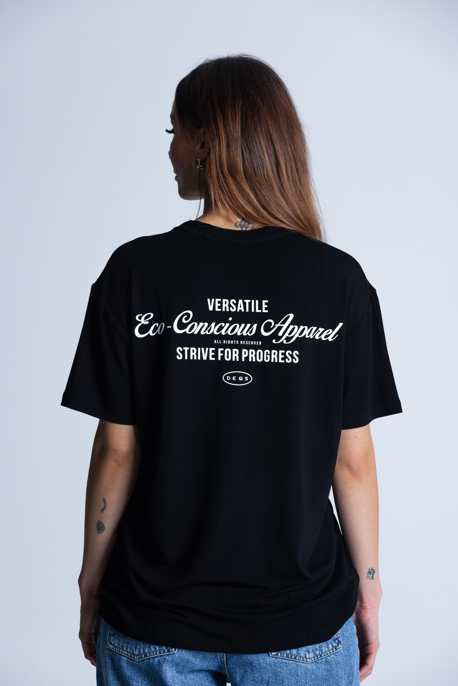 Tył T-shirtu DEQS – nadruk „Versatile / Eco Conscious Apparel”