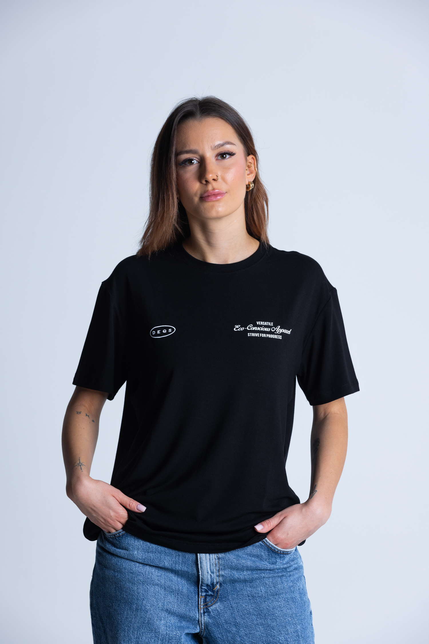 Kobieta w T-shircie DEQS – logotyp + „Eco Conscious Apparel”