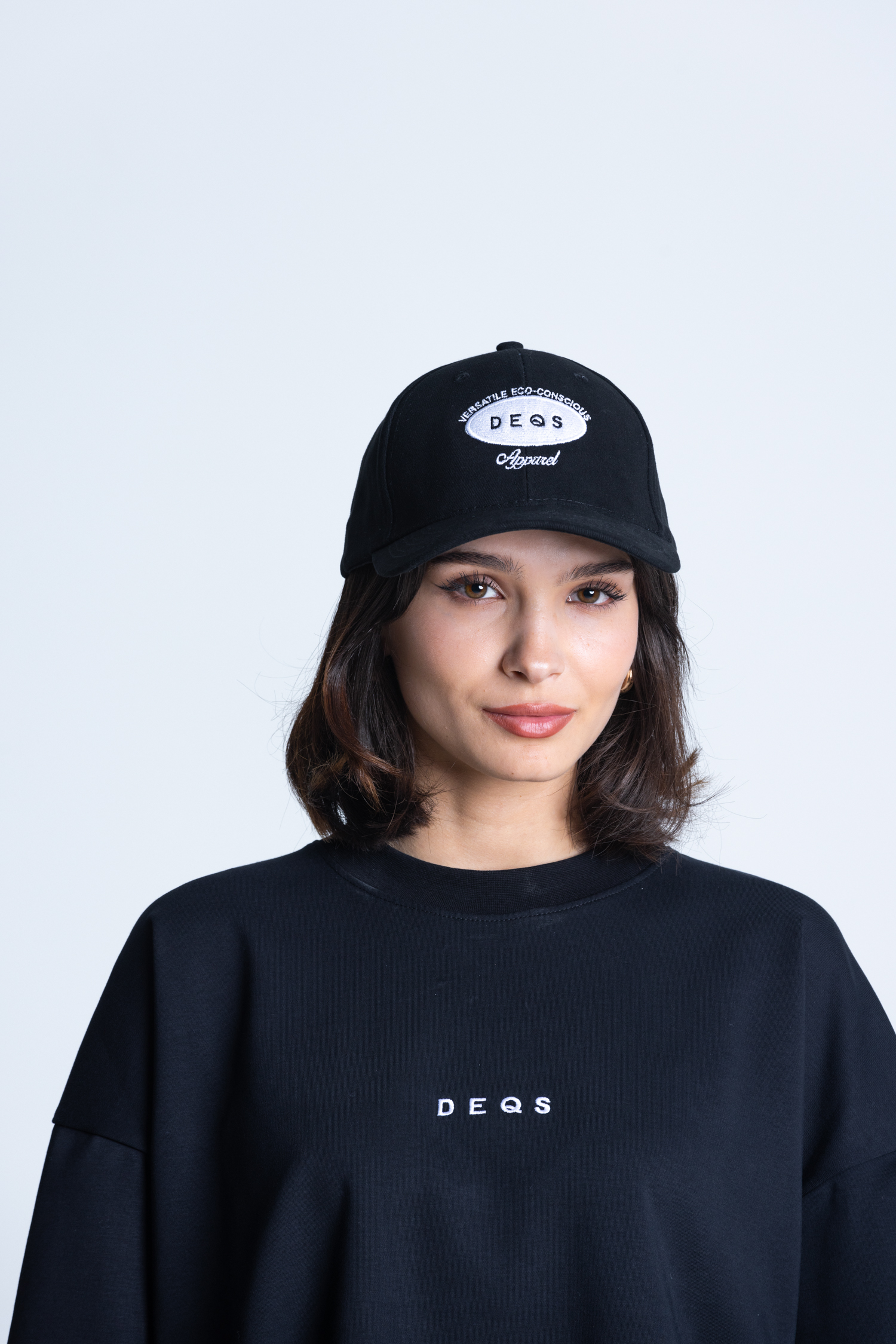 Kobieta w czapce i koszulce DEQS – zestaw streetwear z logotypem