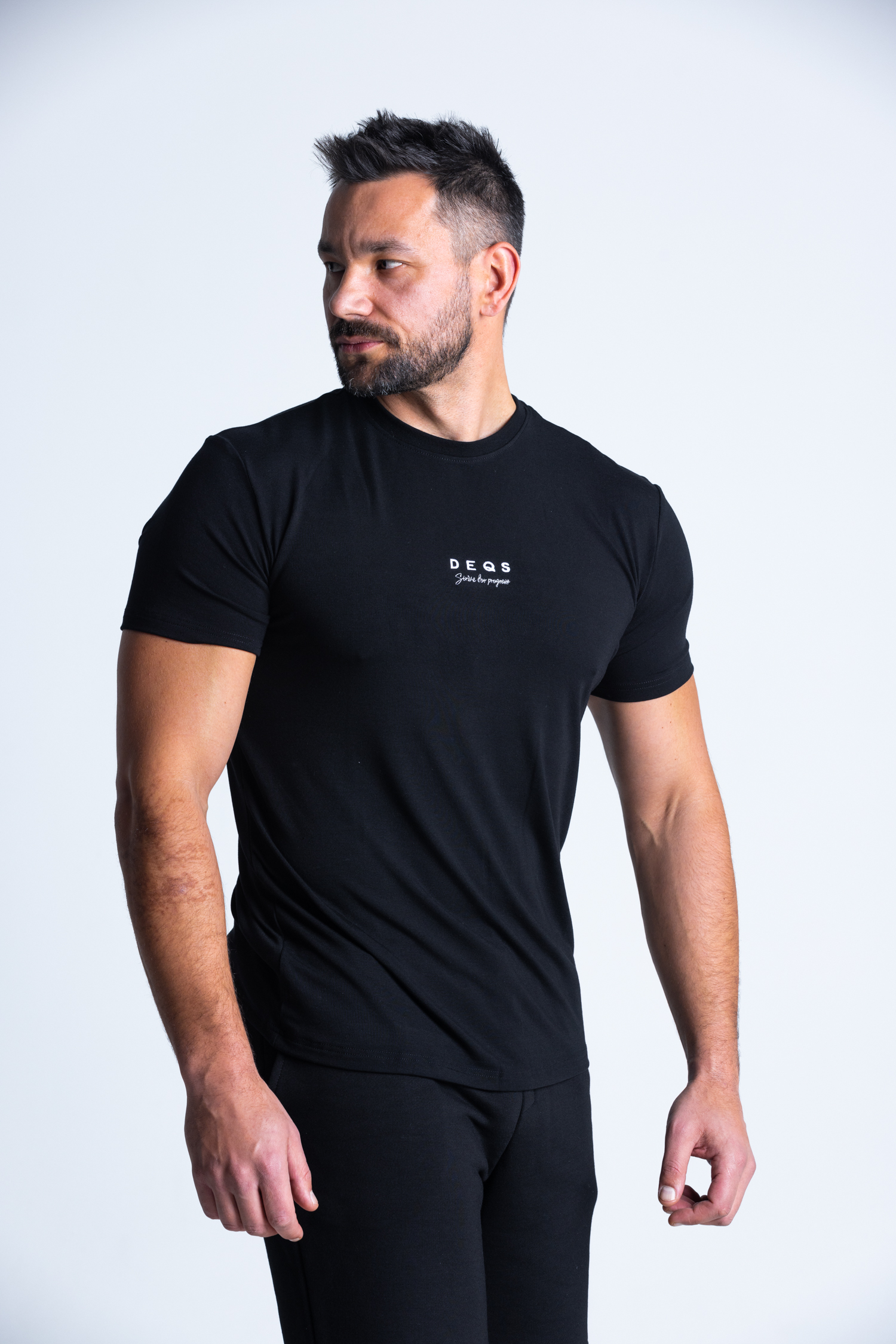 Mężczyzna w koszulce DEQS – hasło „Strive for Progress” na piersi