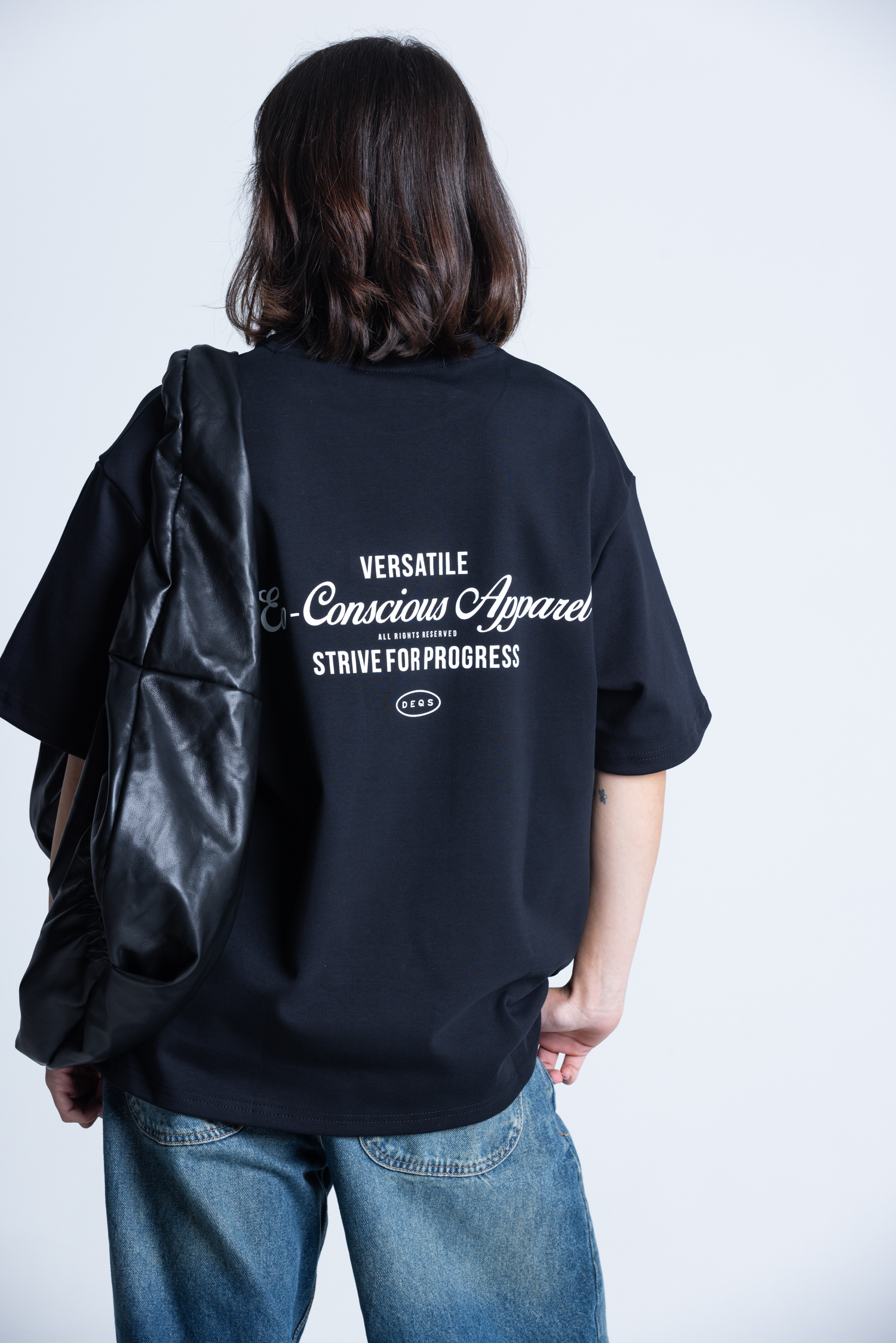 Modelka w T-shircie DEQS z plecakiem – hasło „Eco Conscious Apparel” jako element designu